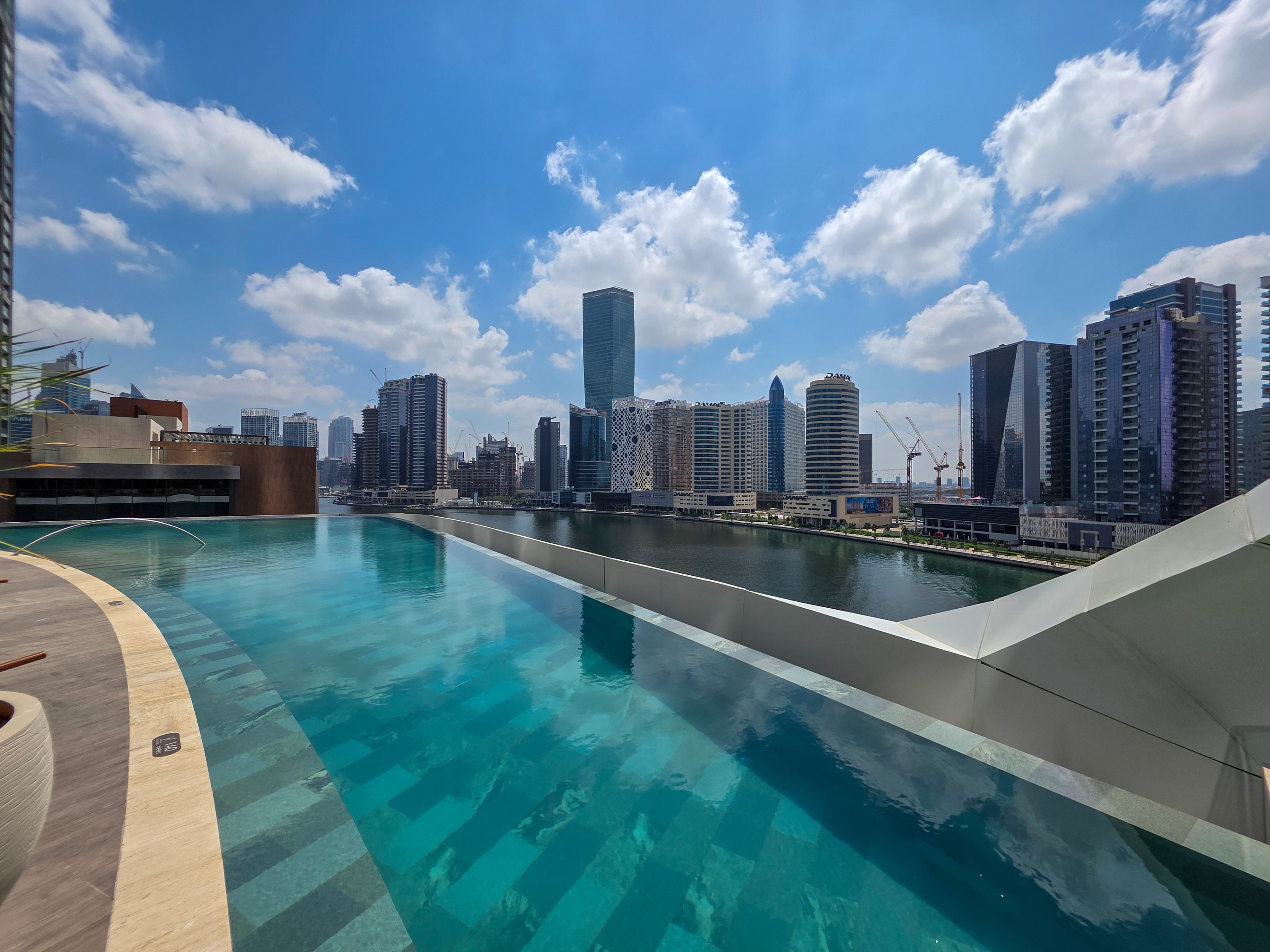 rooftop pool area with a large TV wall and luxury lounge seating - luxury high rise