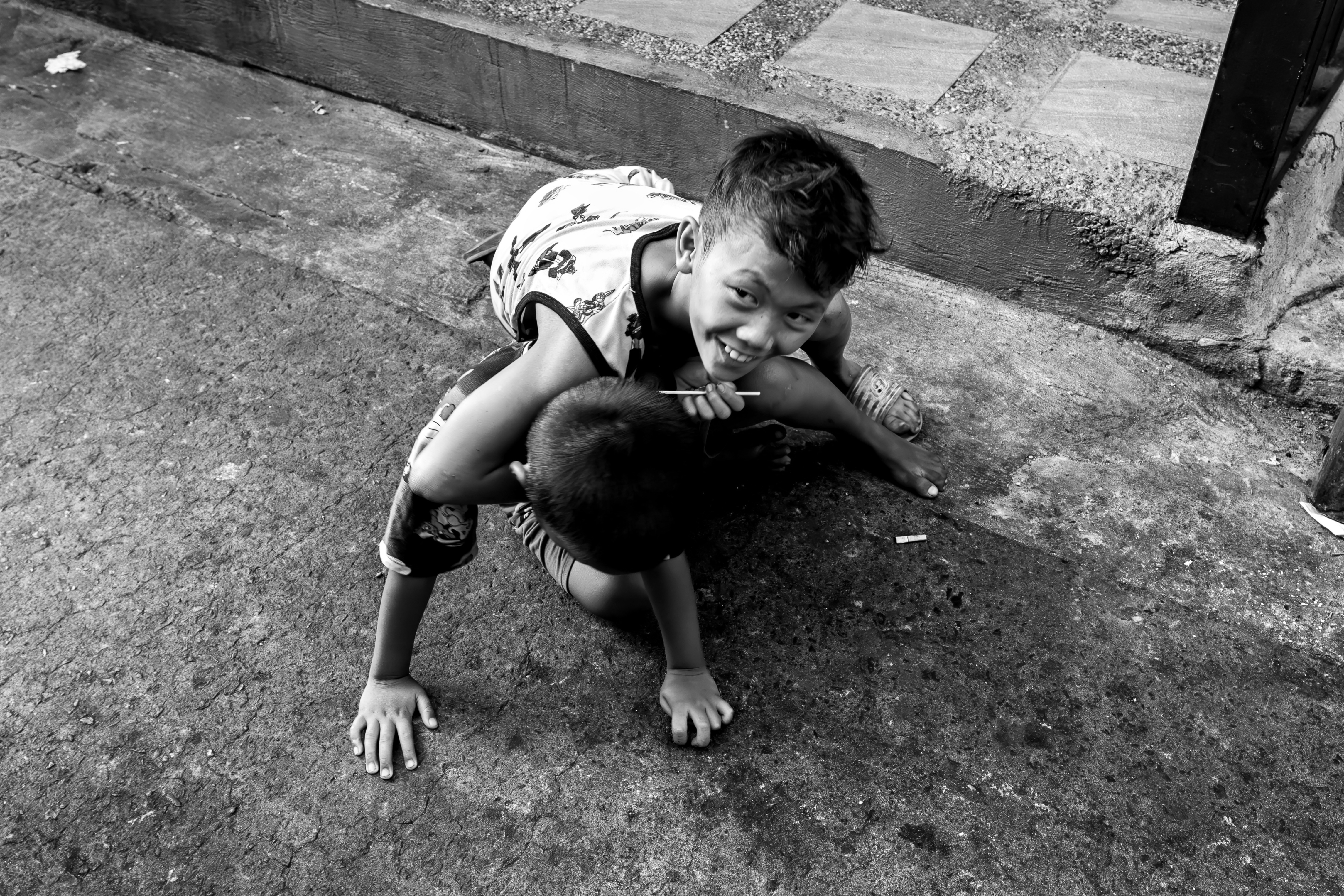Black and white photo of two boys joyfully playing on a city street.