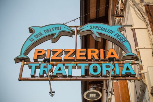 Vibrant sign for 'Ai Due Delfini Pizzeria' captured in Palmanova, Italy.