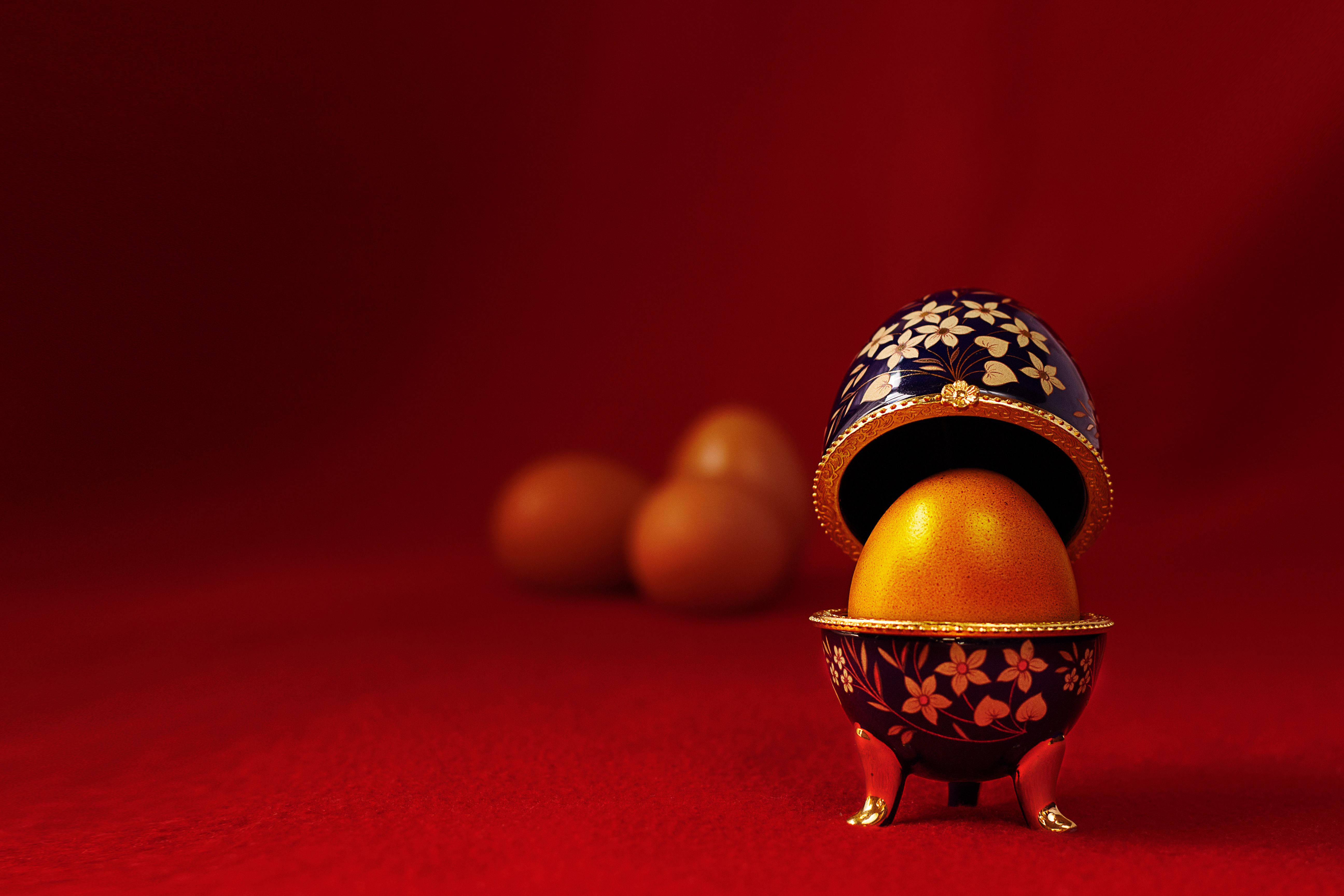 Elegantly designed Fabergé-inspired egg on rich red background symbolizing luxury.