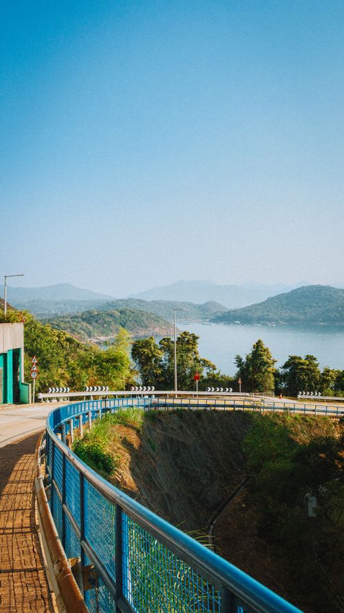 Free Beautiful winding road offering a stunning view of a serene lake and surrounding mountains. Stock Photo