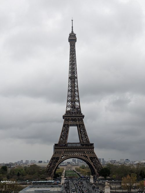 Free Iconic Eiffel Tower in Paris, captured against a backdrop of overcast skies, showcasing its architectural brilliance. Stock Photo