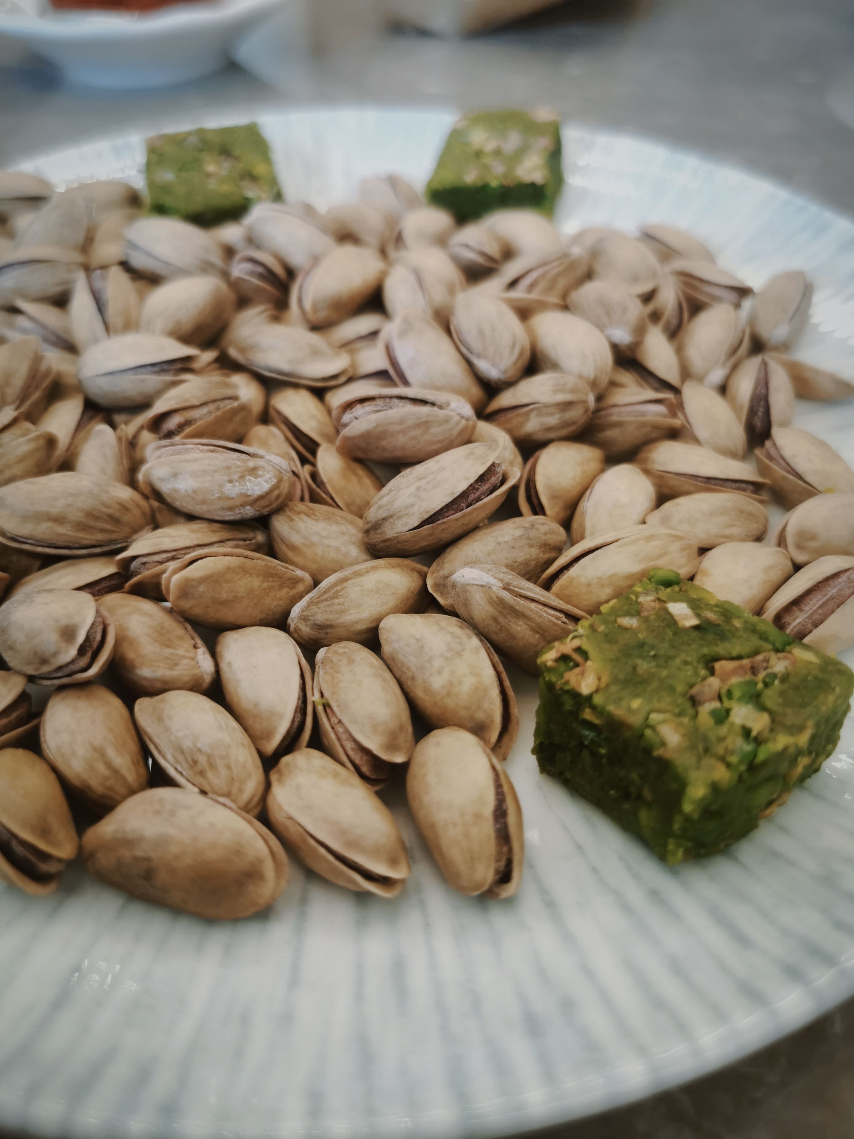 Close-up of pistachios with green sweets on a plate, perfect for snack-related content.