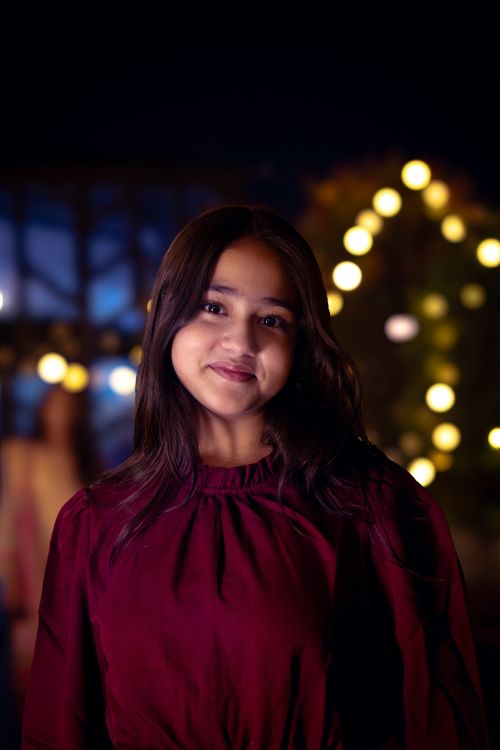 Free Smiling young woman in evening attire with lights in the background. Perfect for lifestyle or fashion themes. Stock Photo