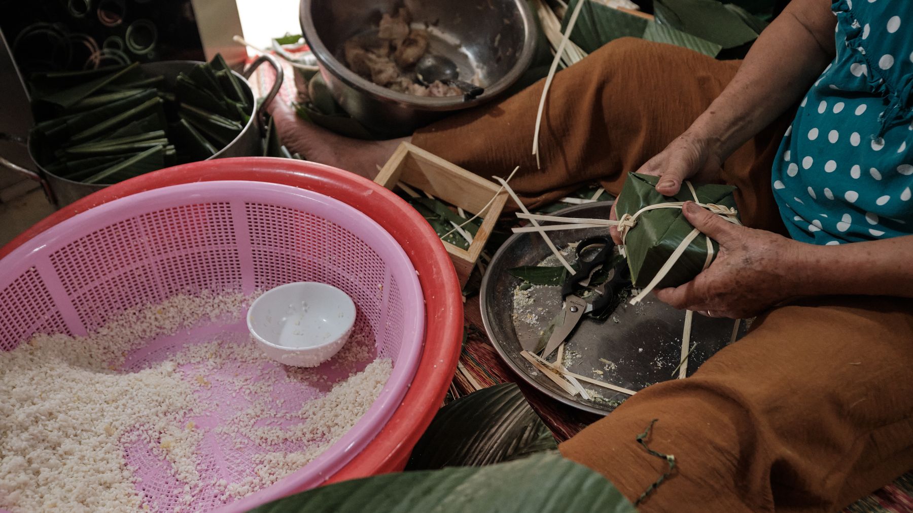 Una donna che prepara le tradizionali torte Chung vietnamite con foglie di banano e riso glutinoso in Vietnam.