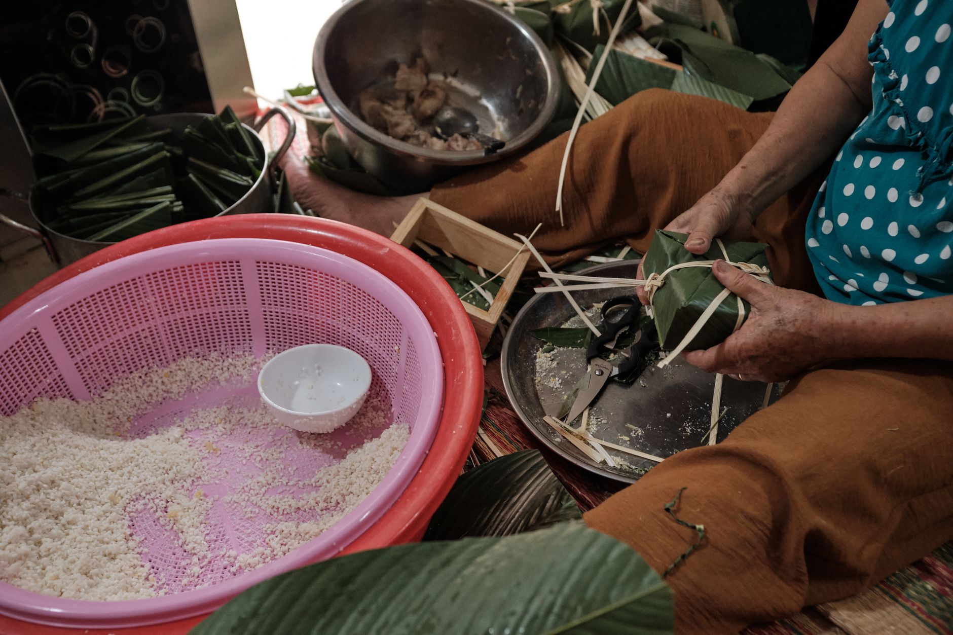 A woman crafting traditional Vietnamese Chung cakes with banana leaves and sticky rice in Vietnam.