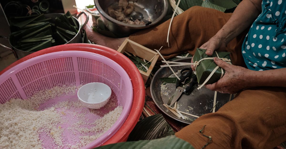 woman smiling at morning market in Vietnam with banana leaf wrapped food