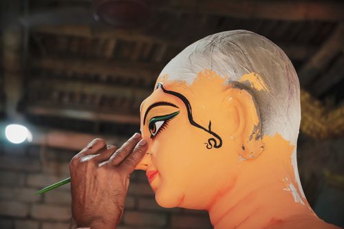 Free Artist meticulously painting a traditional Durga idol in a Kolkata workshop, capturing cultural craftsmanship. Stock Photo