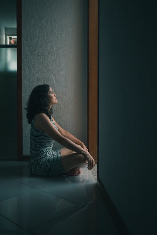 Side View Photo of Woman Sitting on Floor In Front of Doorway With Her Legs Crossed 