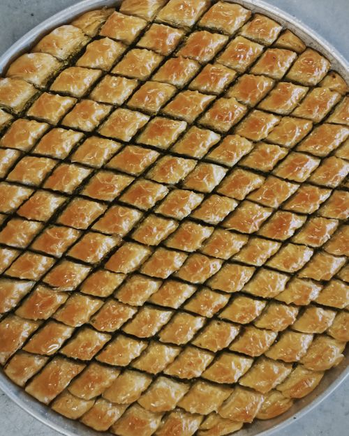 Free Top view of a full round tray with neatly arranged pieces of freshly baked baklava, glistening with syrup. Stock Photo