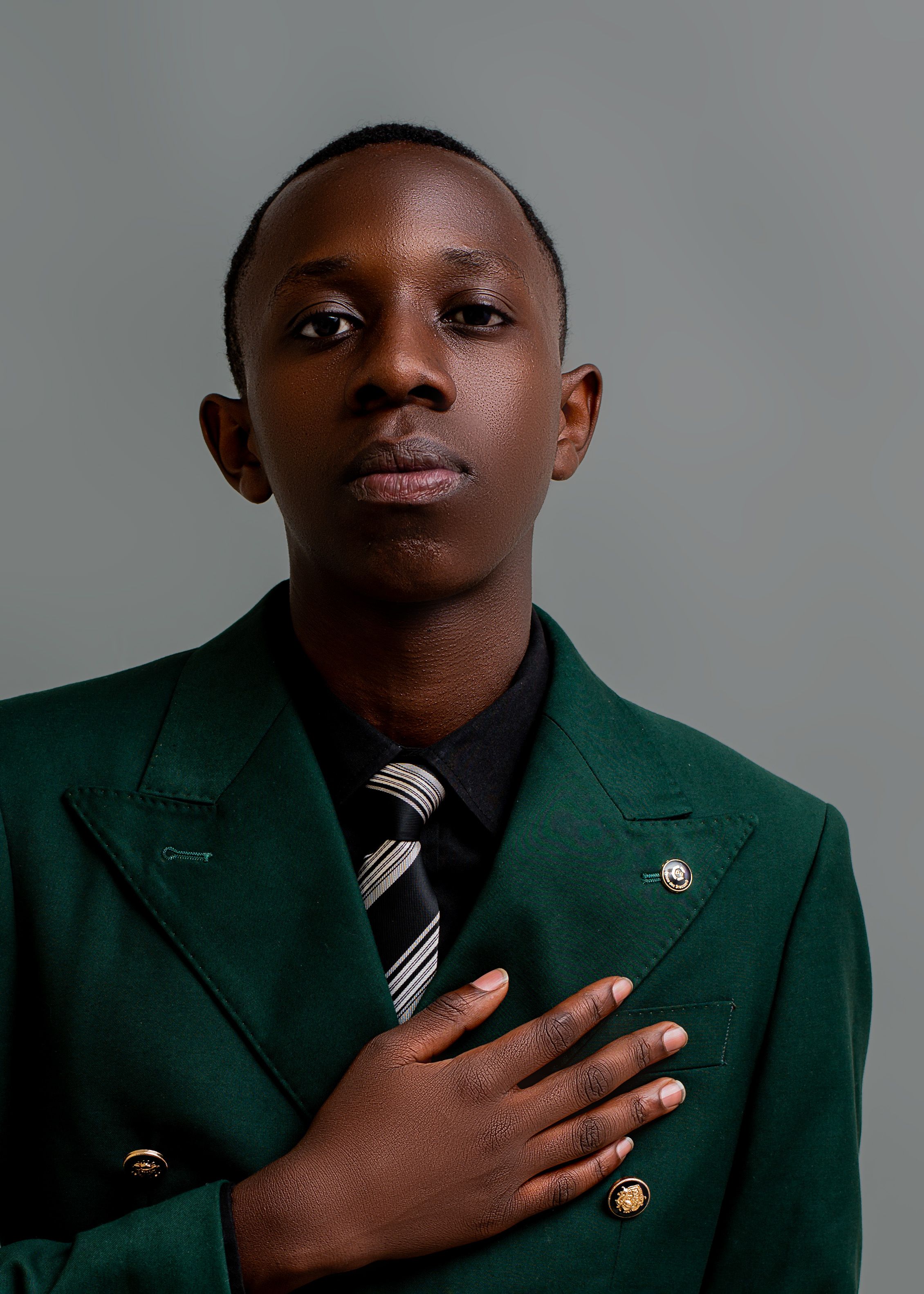 Elegant portrait of a young man wearing a green suit and tie against a neutral backdrop.