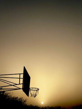 A striking silhouette of a basketball hoop against a vibrant sunset sky in Nigeria.