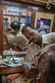 A barber skillfully shaving a man in a traditional shop in Varanasi, India.