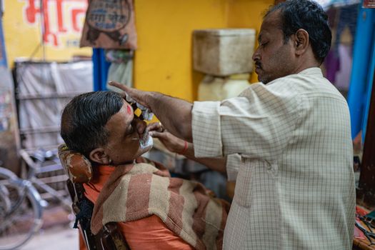 Experience a traditional shave in a vibrant Varanasi barber shop.