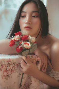 A beautiful woman holding a bouquet of roses in a serene indoors setting.