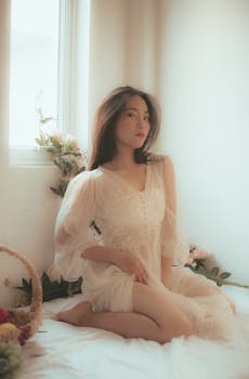 一位优雅的女人穿着透明连衣裙，在光线柔和的房间里优雅地坐着