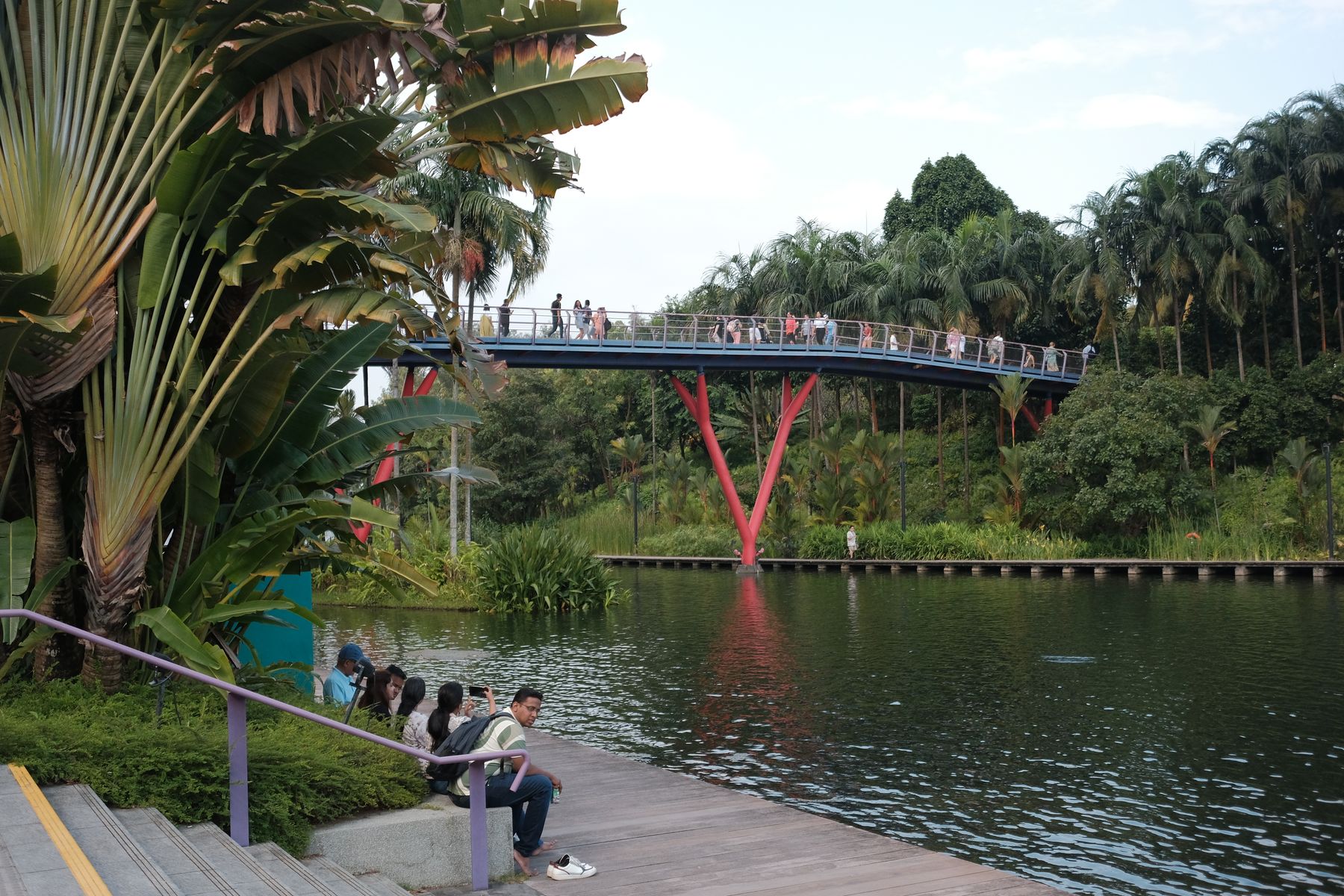 People crossing an elevated walkway through lush tropical gardens in Singapore