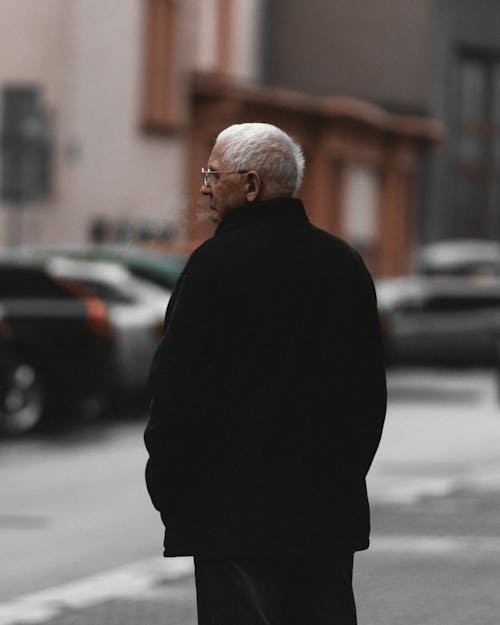 立っている黒いジャケットの老人の選択的なフォーカス背面図写真
