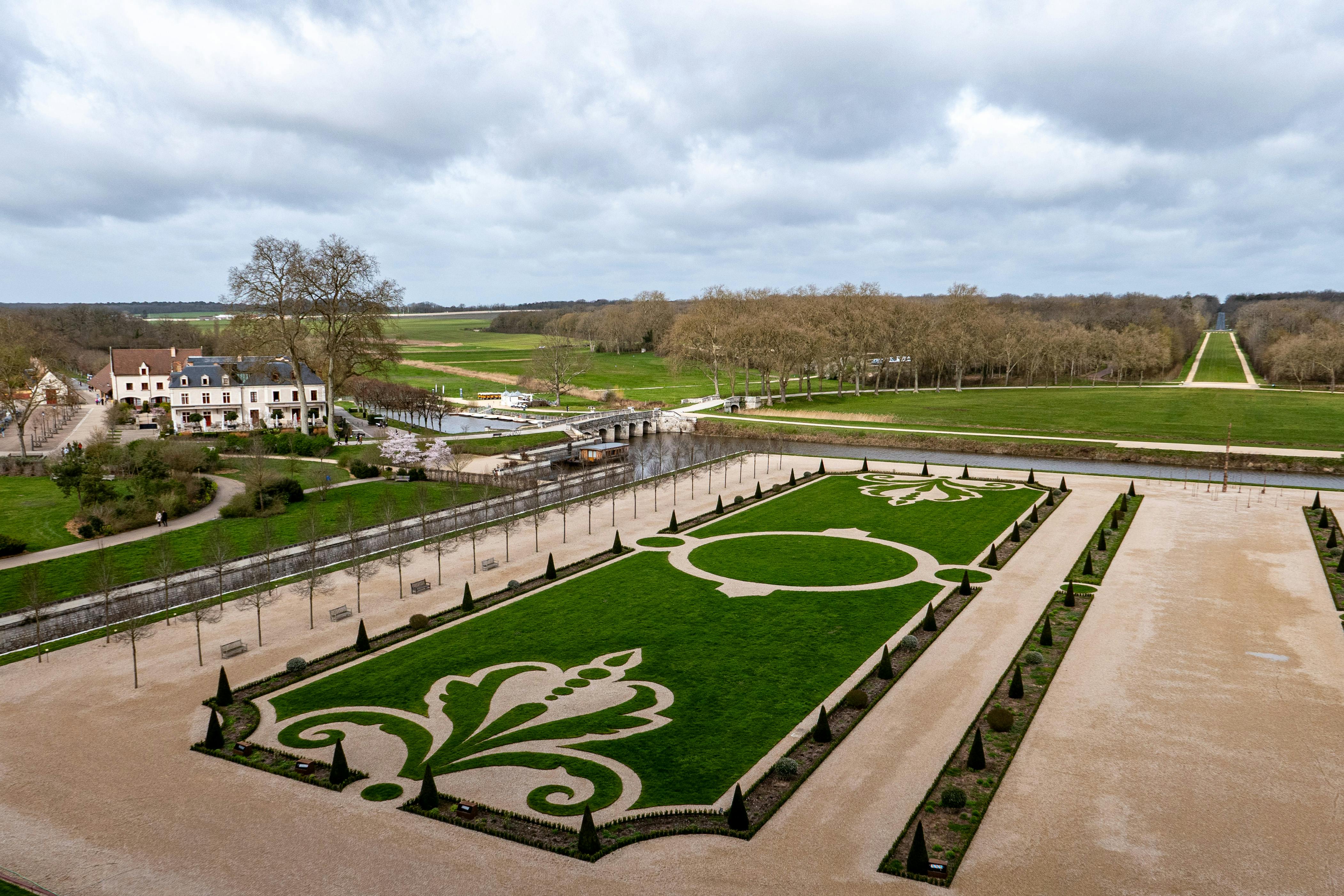 Вид с воздуха на регулярные сады и окружающий ландшафт Château de Chambord под облачным небом, Chambord, Франция