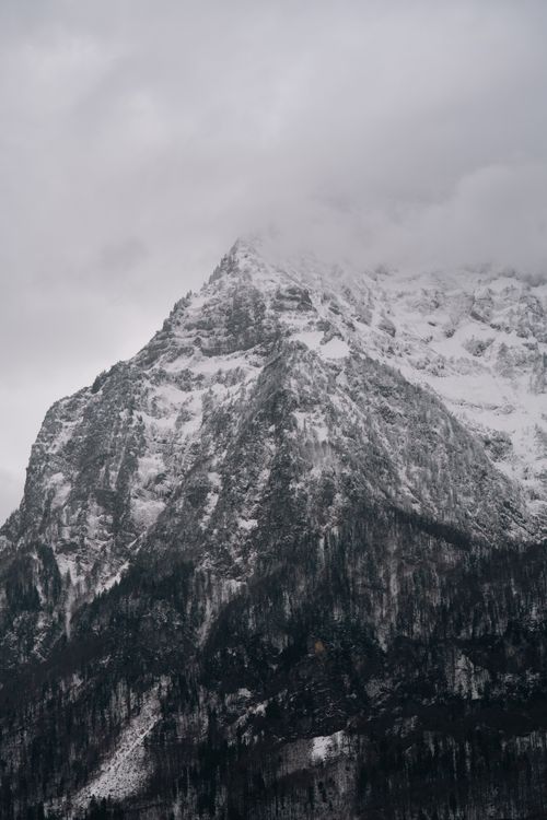 Free Breathtaking view of a snow-covered mountain peak with overcast sky. Stock Photo