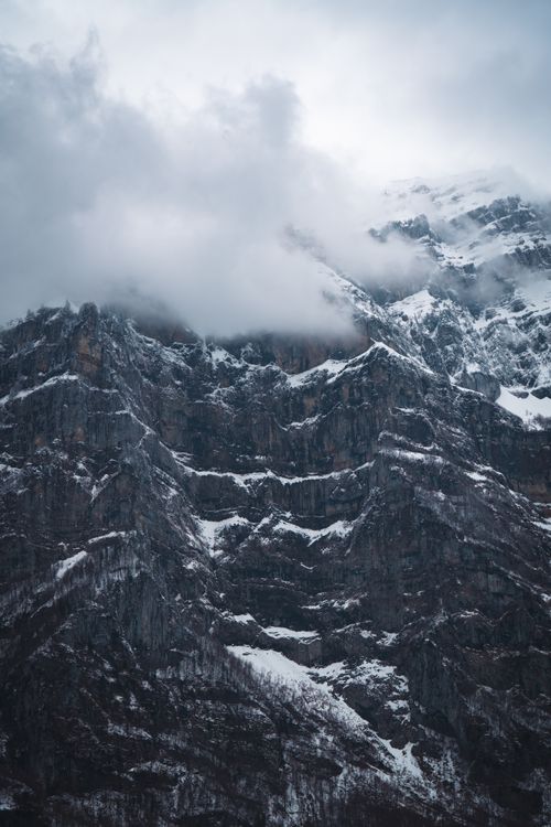 Free Dramatic snow-covered mountains with clouds shrouding their rugged peaks. Stock Photo