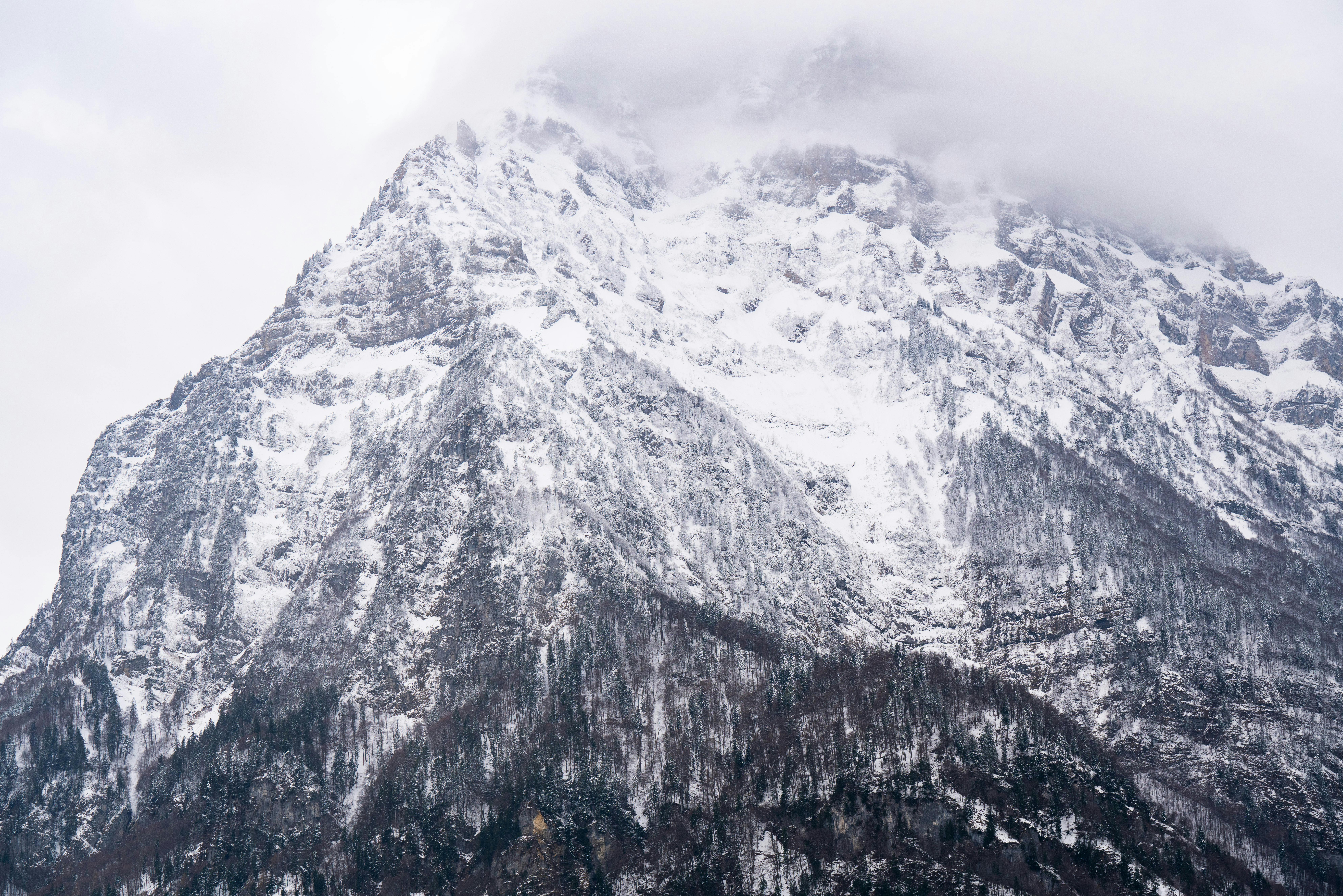 A stunning view of a snow-covered mountain peak enveloped in clouds, captured during winter.