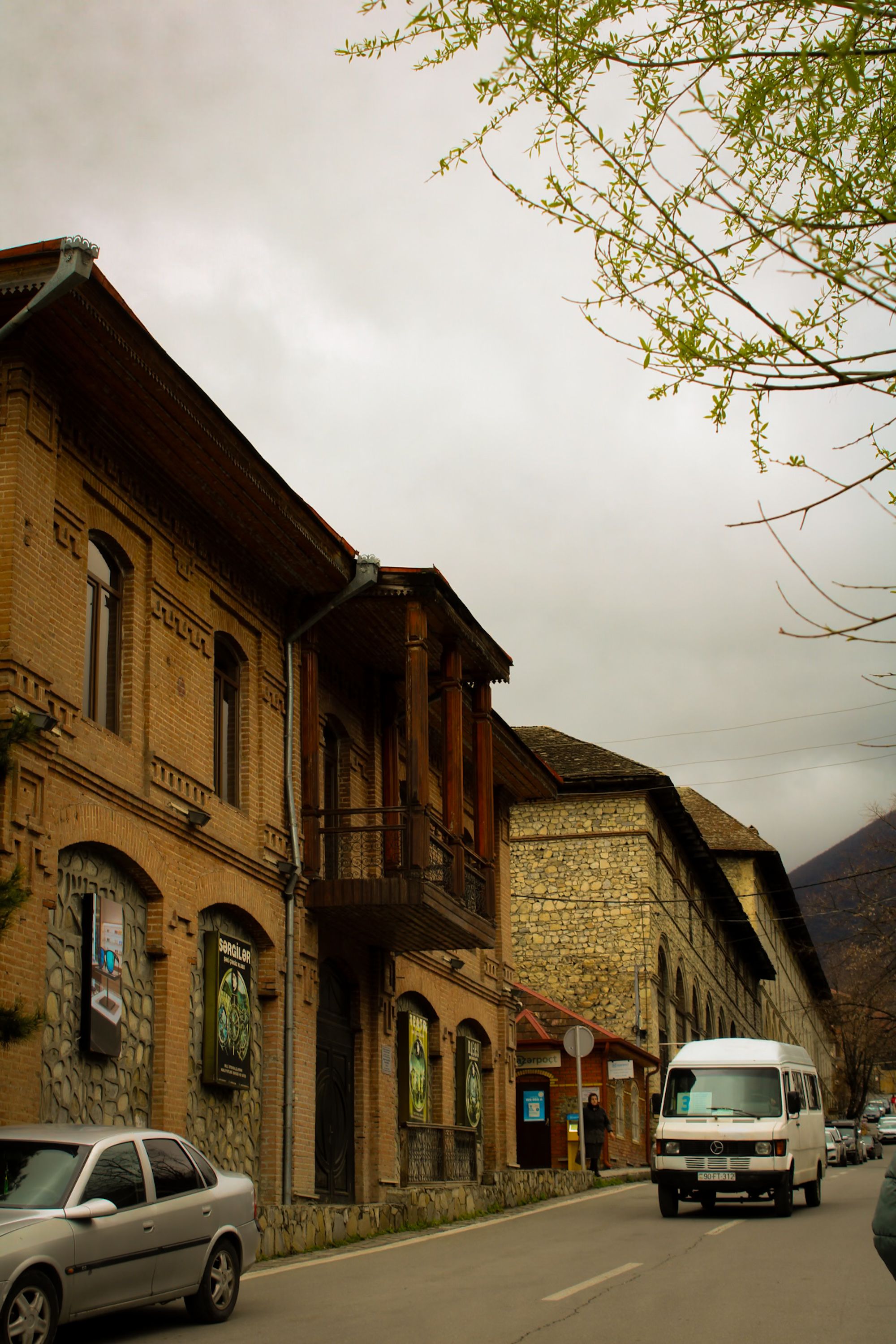 Charming street in Şeki, Azerbaijan showcasing historic architecture with overcast sky.