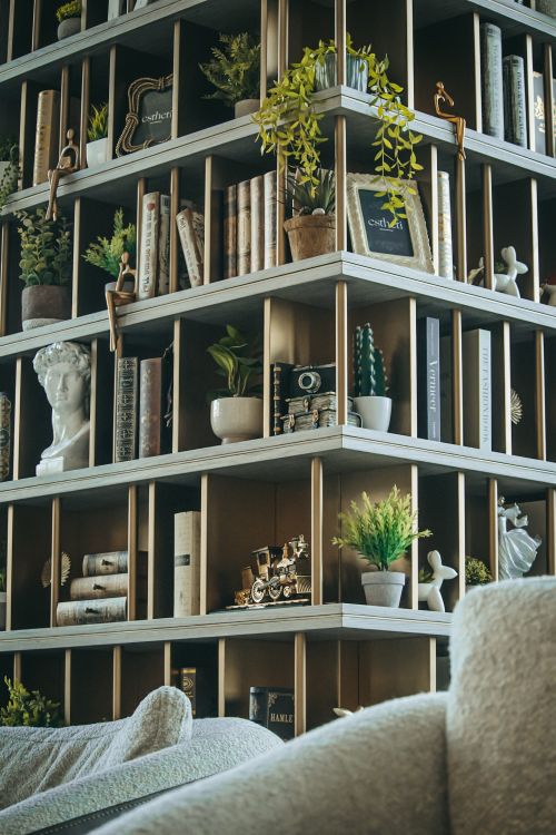 Free A stylish bookshelf filled with plants, books, and sculptures, enhancing a cozy living room atmosphere. Stock Photo