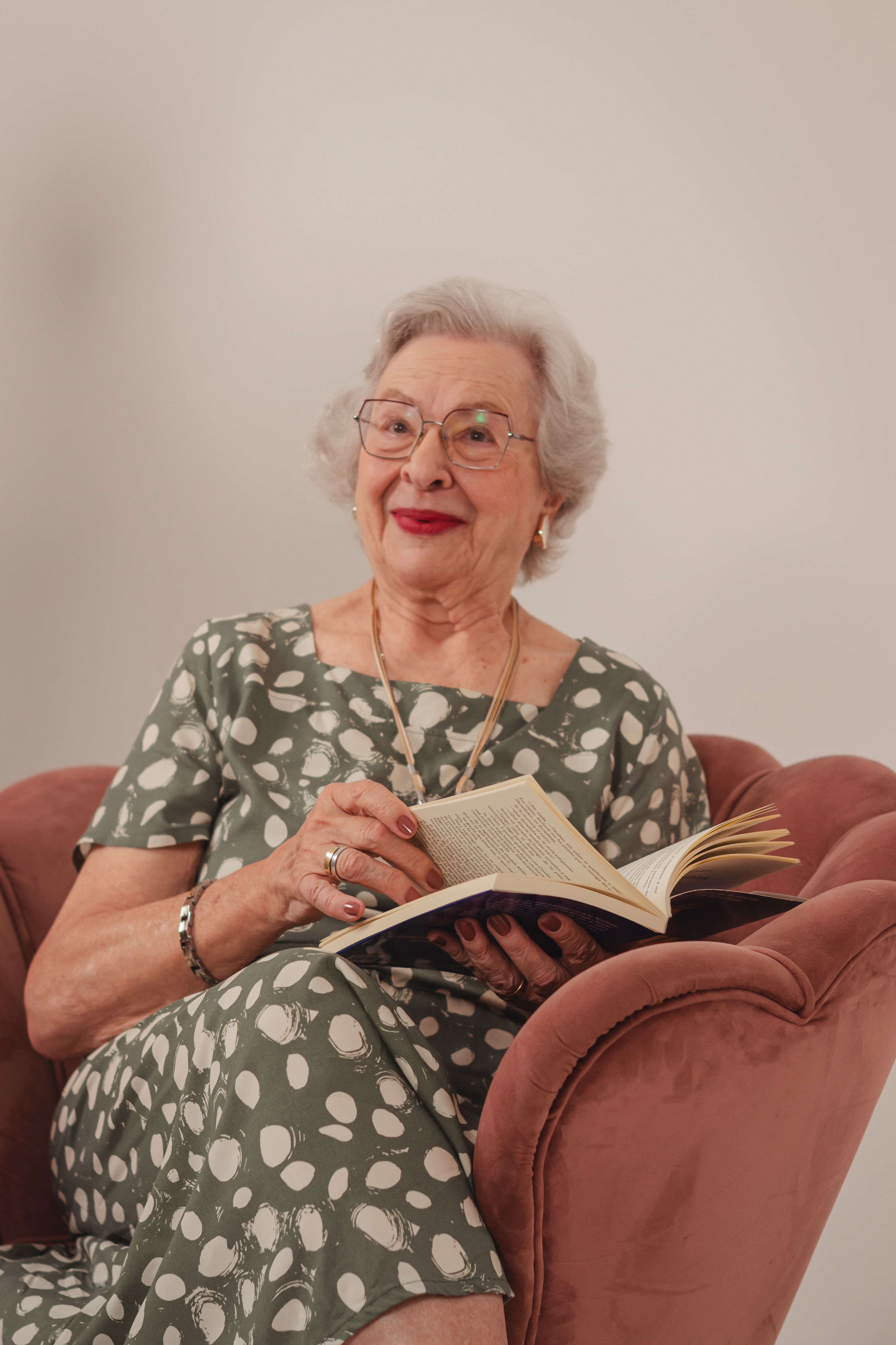 A senior woman reading a book at home in a cozy chair