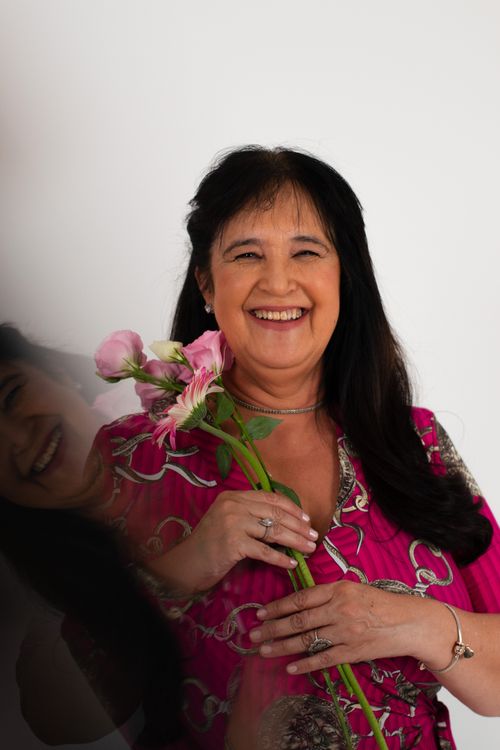 Free Joyful woman in pink dress holding fresh flowers against white background. Stock Photo