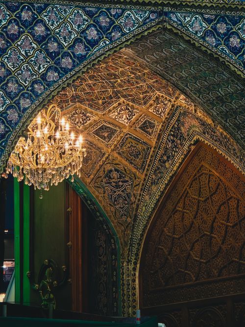 Free Stunning intricate Islamic arch with ornate patterns and a crystal chandelier illuminating the space. Stock Photo