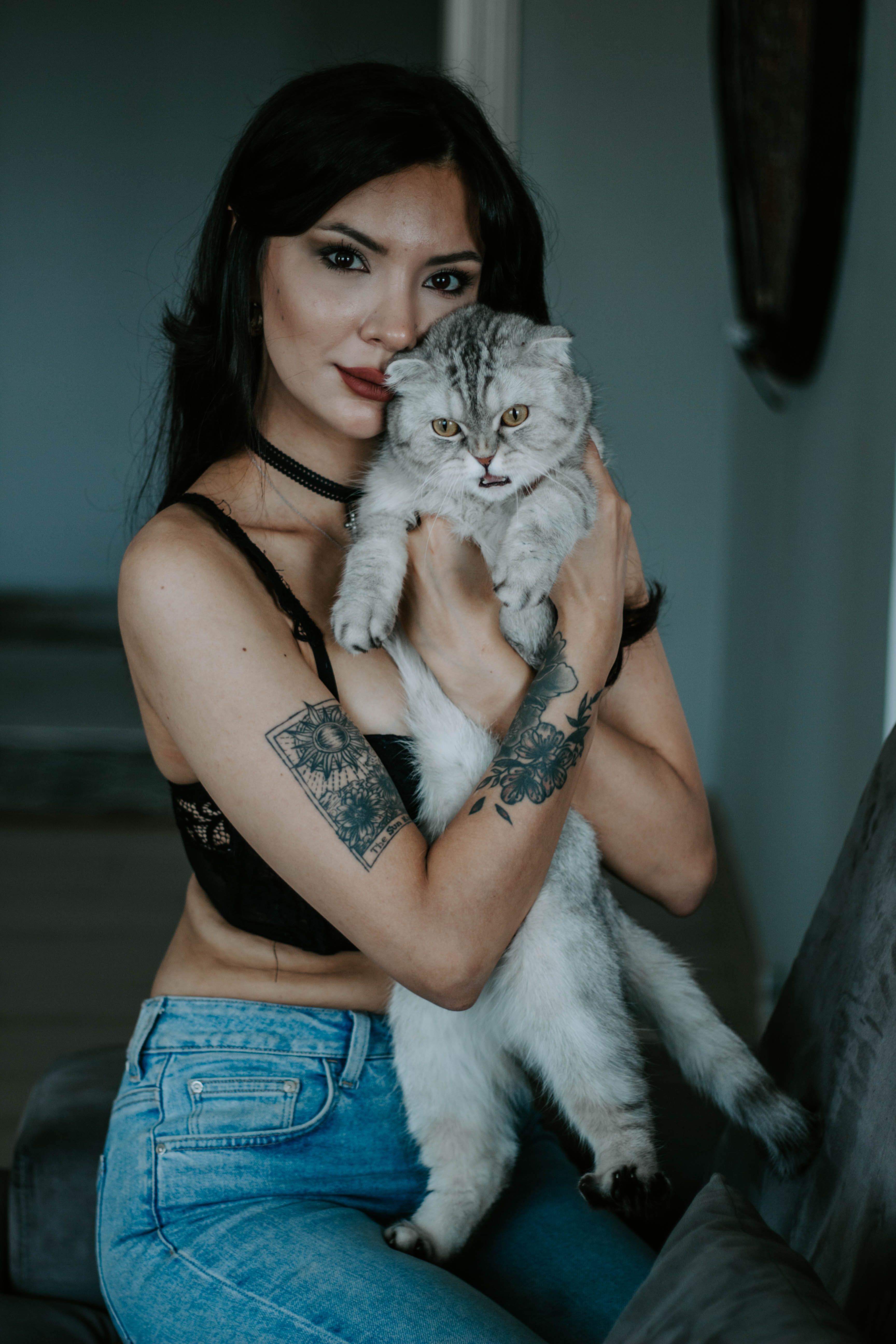 A stylish woman with tattoos holding a fluffy cat indoors in Istanbul.