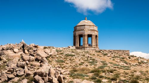 Free Historic stone gazebo atop a rocky hill with blue sky in the background. Stock Photo