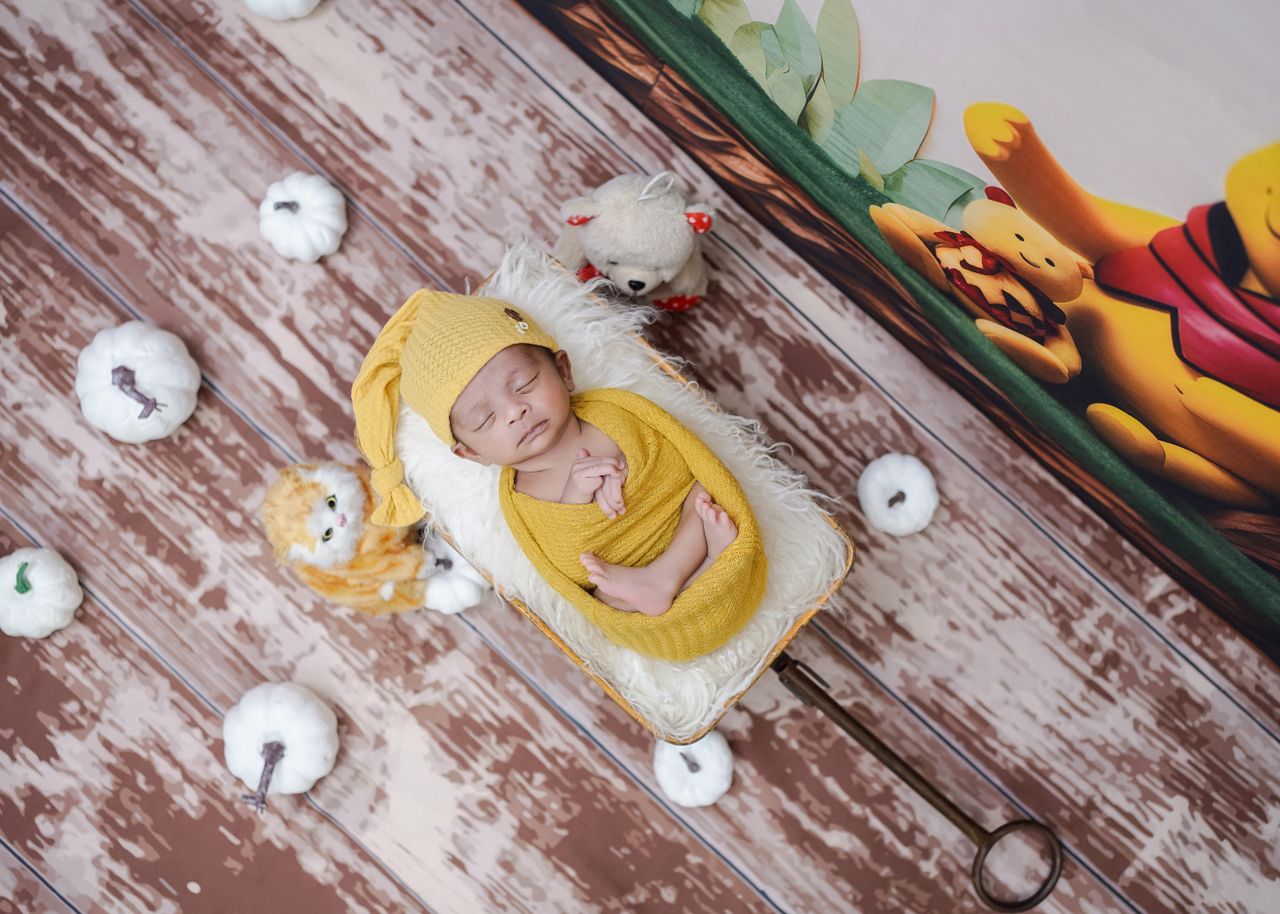 a peaceful sleeping baby wrapped in a yellow outfit surrounded by soft