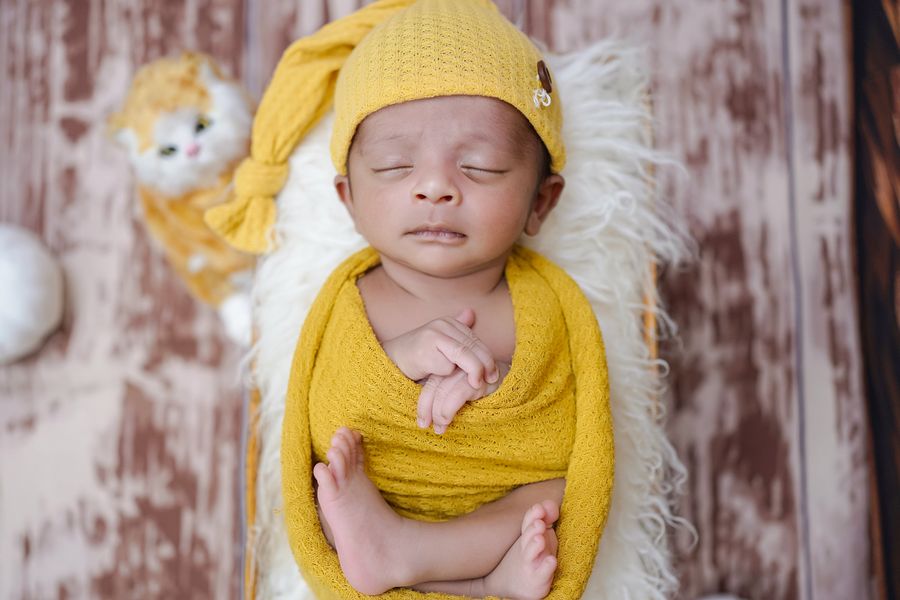 Newborn photography — sleeping baby wrapped in a soft knitted wrap