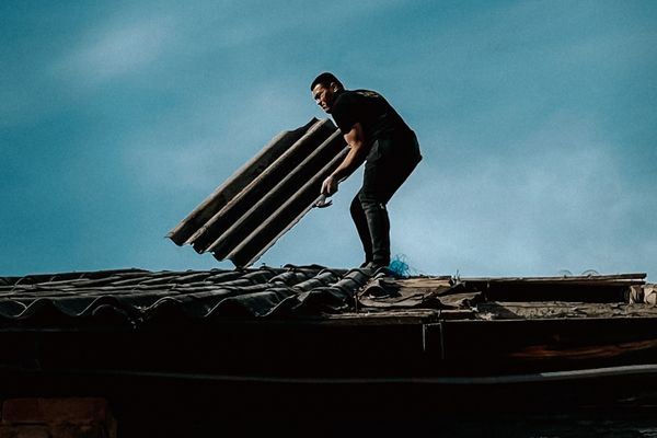 Man inspecting rooftop under blue sky