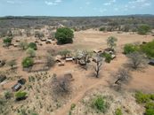 Aerial shot of a rural African village with traditional huts and sparse vegetation.