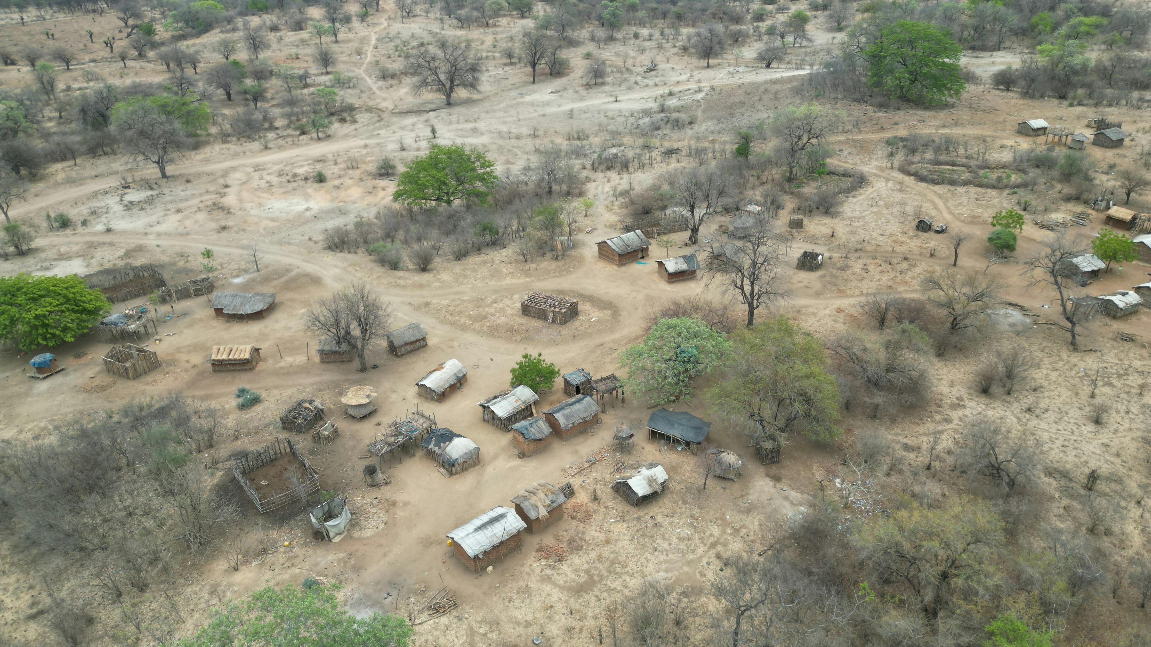 Aerial view of a rural village in Africa, showcasing traditional huts amidst dry landscape.