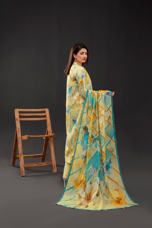 Free Woman in elegant floral traditional attire standing near a wooden chair indoors. Stock Photo