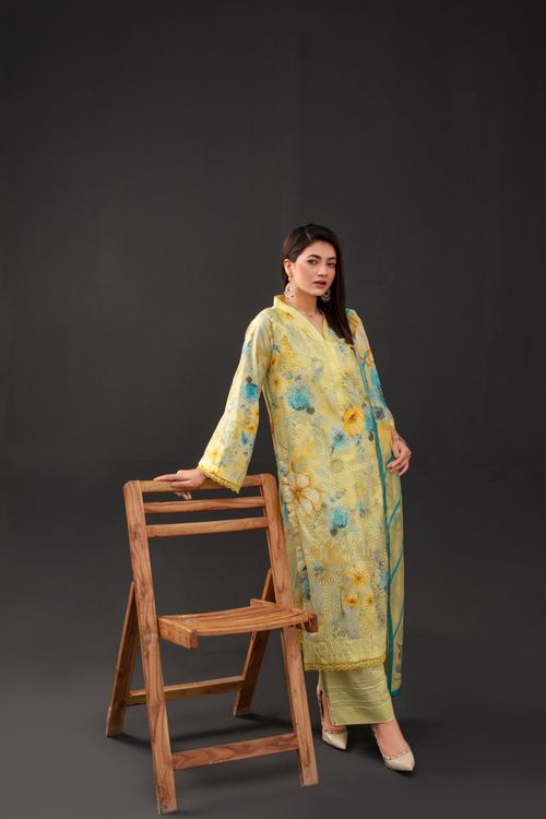 Free Stylish woman in floral attire poses with a wooden chair in studio setting. Stock Photo