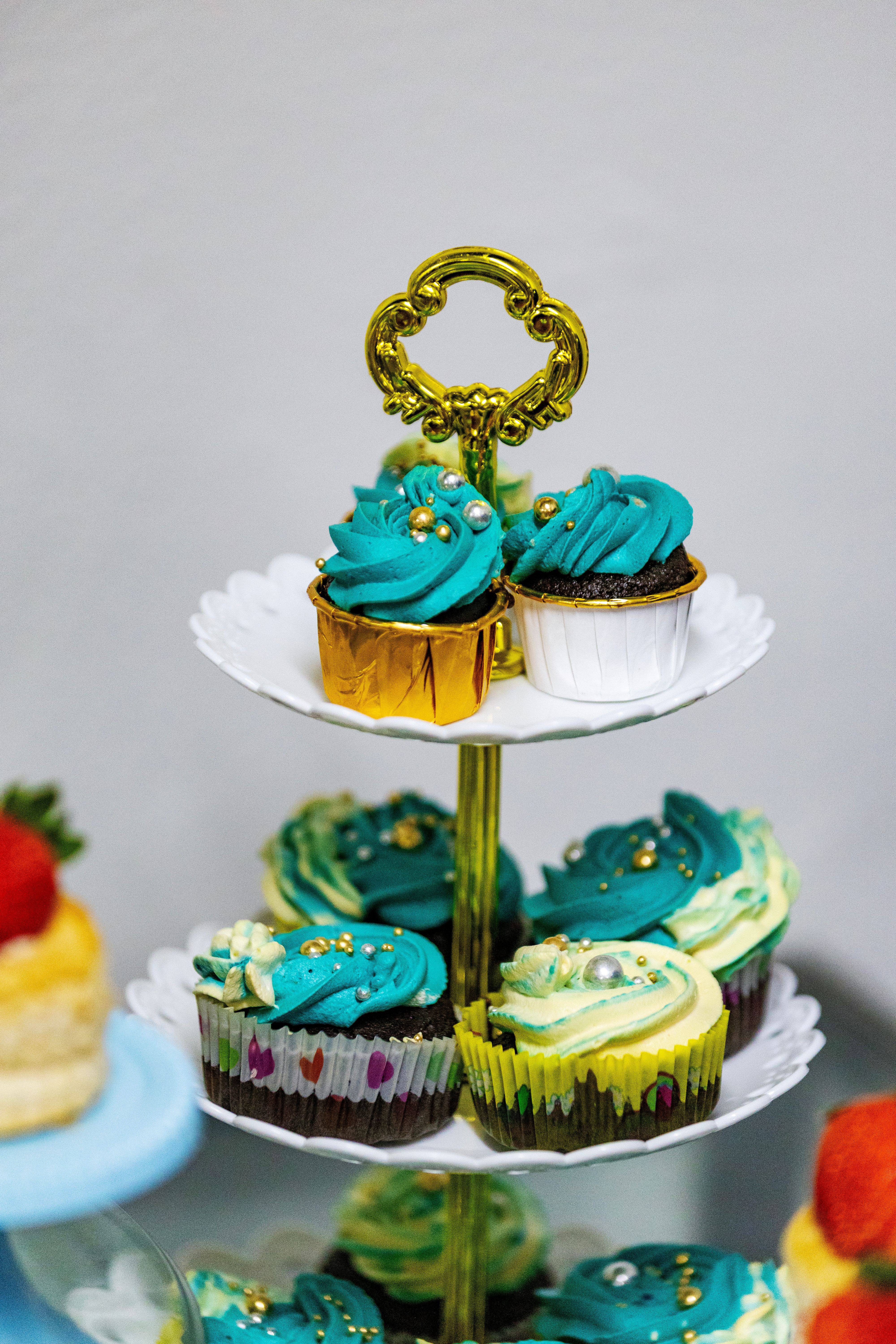 Colorful cupcakes on a tiered stand with elegant decorations suitable for celebrations.