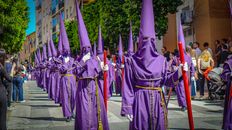 Nazarenos in purple robes participate in a Semana Santa procession in Málaga, Spain.