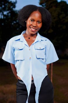 Young woman in a blue top, smiling outdoors with natural background.