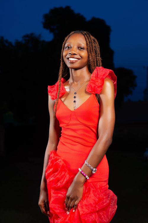 Free Smiling woman in a red dress posing outdoors during twilight. Stock Photo