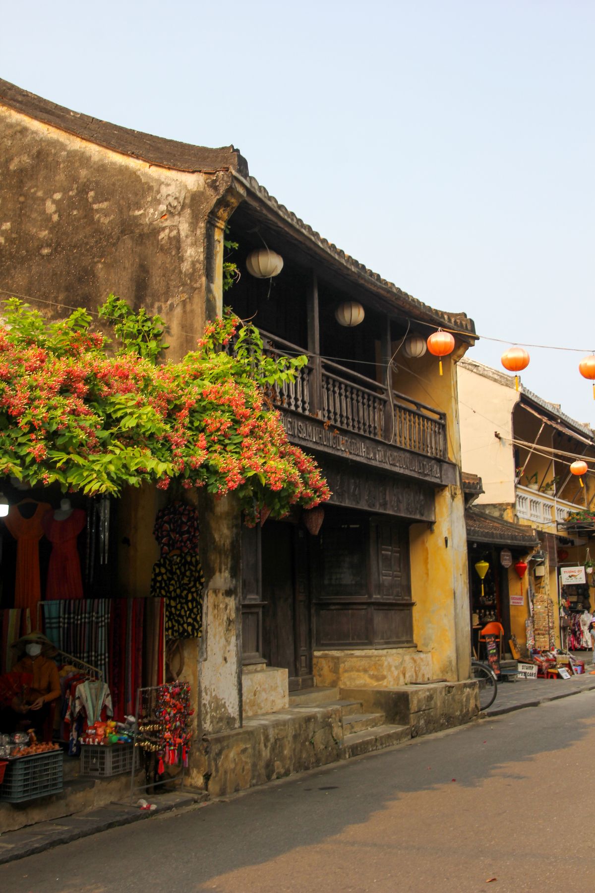 Yellow heritage house with lanterns and flowering plants in Hoi An