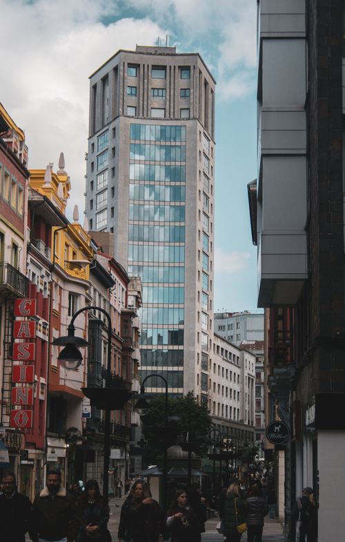Free City street in Oviedo, Spain featuring a modern skyscraper and bustling urban life. Stock Photo