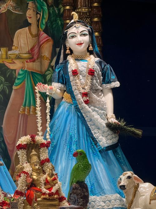 Free A vibrant Indian statue in Tirupati featuring traditional attire, a parrot, and a decorated calf. Stock Photo