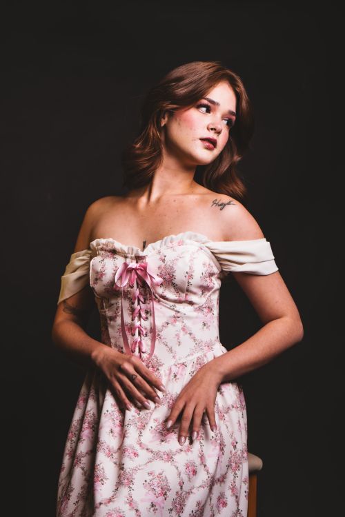 Free Stylish portrait of a woman in a floral off-shoulder dress against a dark background. Stock Photo