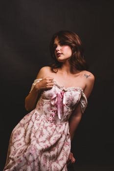 Elegant portrait of a woman wearing a floral dress against a dark background, capturing a romantic mood.