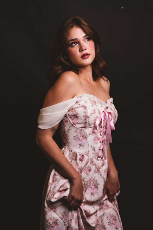 Free Elegant woman in a floral dress looking contemplative against a dark backdrop. Stock Photo